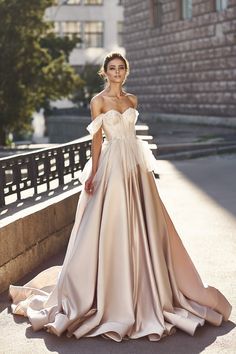 a woman in a long dress standing on the sidewalk