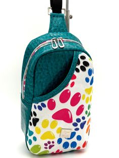 the back side of a colorful backpack with paw prints on it's front pocket