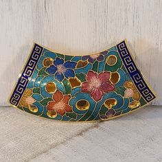 a decorative blue and red flowered dish on a white surface next to a wooden door