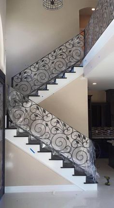 a stair case in the middle of a room with a chandelier above it