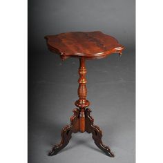 a small wooden table with an ornate design on it's top and legs, in the shape of a pedestal