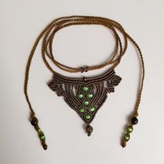 a necklace with green beads is hanging on a white surface