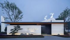 the entrance to a modern home with deer on it's roof and trees in the background