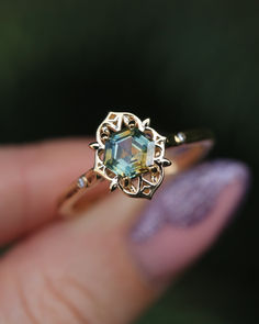 A close-up image showing a custom 14K yellow gold engagement ring from Staghead Designs. This ring has a hexagon cut bi-color Montana sapphire that is teal and yellow set in a mandala-like metal setting with two diamond accents. Whiskey Barrel Wedding Ring, Green Engagement Rings, Antler Wedding Rings, Antler Wedding Band, Ring Photo, Handcrafted Engagement Ring, Wood Wedding Ring