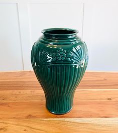 a green vase sitting on top of a wooden table