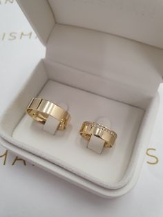 two gold rings sitting in a white box