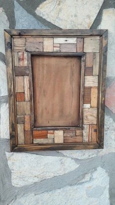 a small wooden frame sitting on top of a stone wall