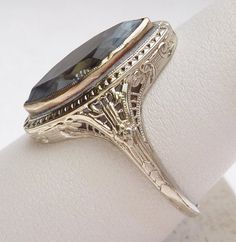 A beautiful ring from the Art Nouveau period. This ring features a man made marquise shape blue stone. Stone does have a scratch on the table. The marquise stone is bezel set in a beautiful filigree mounting. All the detail of the mounting is in excellent condition. The marquise stone measures approximately 17.5 x 7.25 mm. This piece is 18 karat white gold and weighs 4.0 grams. Ring is currently a size 10 3/4. Marquise White Gold Sapphire Ring, White Gold Marquise Sapphire Ring, Art Deco Oval Rose Cut Diamond Jewelry, Vintage Blue Marquise Sapphire Ring, Oval Rose Cut Diamonds Art Deco Jewelry, Heirloom Sapphire Ring Marquise Cut, Art Deco Marquise Hallmarked Jewelry, Gift Marquise Diamond Cut Sapphire Ring, Marquise Diamond Cut Sapphire Ring Gift