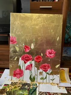 a painting with red flowers on it sitting on top of a table next to a tv