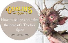 a person holding up a fake troll head in front of a white brick wall with the words goblins live on it