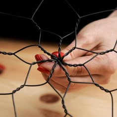 a woman's hand holding onto a wire fence