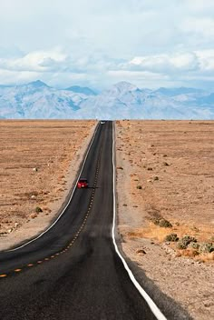 an empty road in the middle of nowhere, with mountains in the backgroud