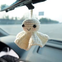 a crocheted stuffed animal hanging from the dashboard of a car with its eyes closed