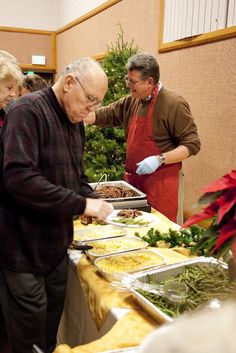 people standing around a table with food on it