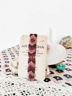 a red and black bracelet sitting on top of a doily next to a plate