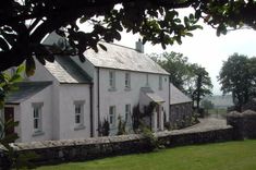 a large white house sitting on top of a lush green field next to a stone wall