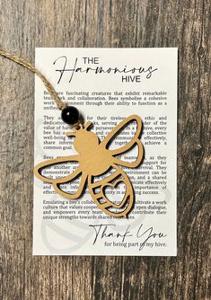 a wooden bee ornament hanging from a string on top of a piece of paper