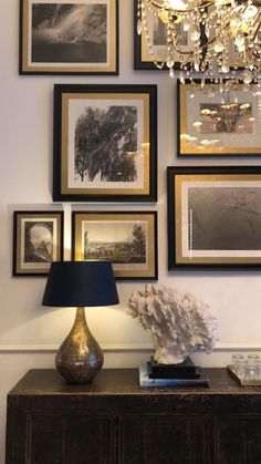 a table with a lamp and pictures on the wall