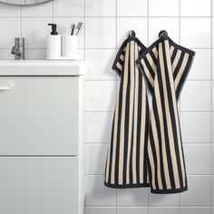 two black and white striped towels hanging on the wall next to a sink in a bathroom