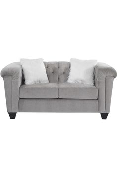 a grey couch with white pillows on it's back and two pillowed cushions