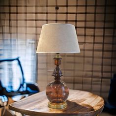 a table with a lamp on top of it and a chair in the back ground