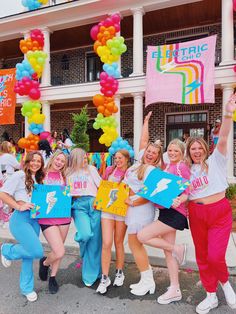 a group of girls holding up signs and balloons in front of a building with flags