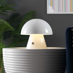 a white mushroom lamp sitting on top of a table next to a potted plant