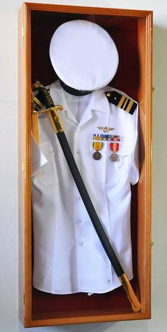 a white shirt and black tie in a wooden box with an officer's medal