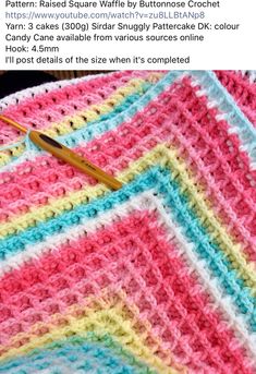 a crocheted blanket with a knitting needle