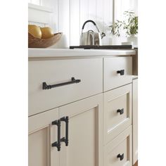 an image of a kitchen setting with white cupboards and black pulls on the handles