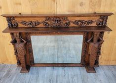 an old wooden fireplace mantle with carvings on the top and sides, in front of a wood paneled wall