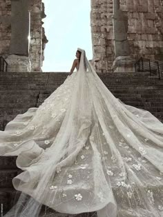 a woman in a wedding dress standing on some steps with her veil blowing in the wind