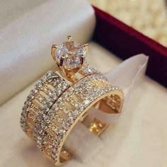 a gold ring with two rows of diamonds on it in a gift box next to a white napkin