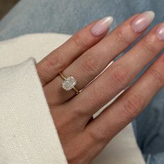 a woman's hand wearing a gold ring with a diamond on the middle finger