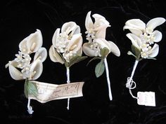 three white flowers with leaves are on a black background and there is a price tag attached to them