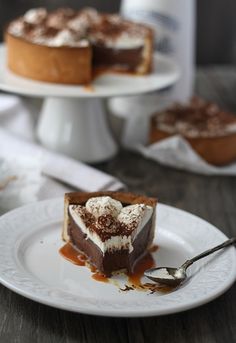 a slice of chocolate cheesecake on a white plate with a fork and bottle of milk in the background