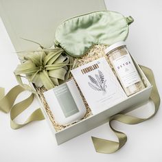 an open gift box containing two bottles of tea and some other items, with a green satin bag next to it