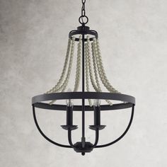 a black chandelier with pearls hanging from it's center and two lights on each side