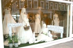 a store window with mannequins dressed in wedding dresses and flowers on display