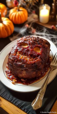 a white plate topped with meat covered in sauce and surrounded by pumpkins on the table