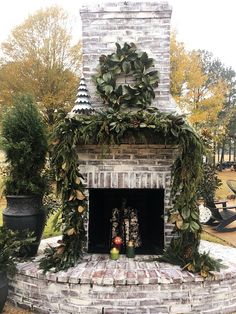 an outdoor fireplace decorated with greenery and candles