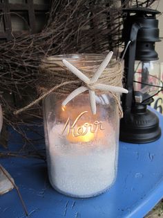 a mason jar with a starfish on it sitting on a blue table next to some branches