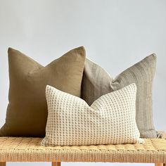 three pillows sitting on top of a wooden bench