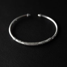 This finely crafted, stackable beauty is delicately adorned with intricate twisted wire detailing. Crafted to be seamlessly stacked with other bracelets, this piece is a versatile addition to your collection.   Design: by NOIR KĀLA Material: 925 Silver Size: 7 cm x 6 cm Weight: 14 g