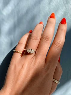 a woman's hand with an orange manicured nail polish holding a diamond ring