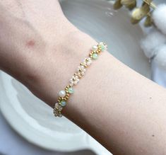 a close up of a person wearing a bracelet with pearls and beads on their arm