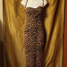 a mannequin wearing a leopard print dress on display in front of a gold curtain