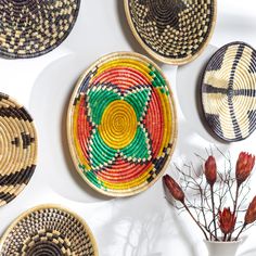 several woven baskets are arranged on the wall next to a vase with flowers in it