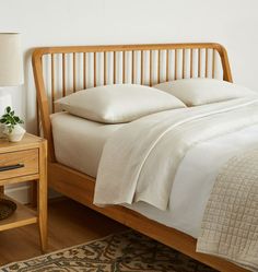 a bed with white sheets and pillows on top of it next to a night stand