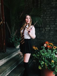 a young woman is posing for a photo in front of some potted plants and flowers